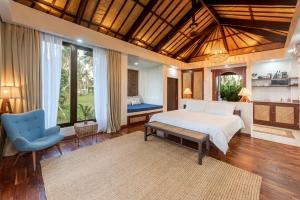 a bedroom with a bed and a blue chair at VILLA JUAN - A Beach Front Villa in General Luna Siargao in General Luna