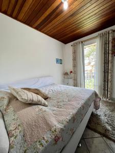 um quarto com uma cama grande e uma janela em Casa verde no centro de Paraty em Paraty
