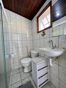 a bathroom with a sink and a toilet and a window at Casa verde no centro de Paraty in Paraty