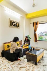 two women sitting on a couch in a living room at The Hosteller Agra in Agra