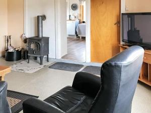 a living room with a black leather chair and a stove at Six-Bedroom Holiday home in Bud in Bud
