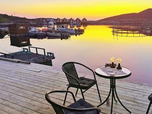 einen Tisch und Stühle auf einer Anlegestelle in der Nähe des Wassers in der Unterkunft 6 person holiday home in Kverva in Dyrvik