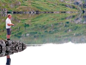 a man is standing in a lake holding a fishing line at 6 person holiday home in Nordli in Holand