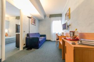 una camera d'albergo con sedia blu e una camera da letto di Hotel Residence Club Primula a Pescasseroli
