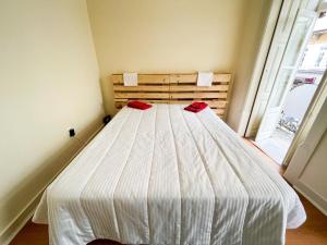 1 dormitorio con 1 cama con sábanas blancas y almohadas rojas en Sweet Love Family Budget en Coimbra