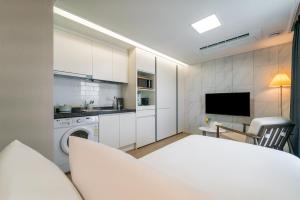 a kitchen with white cabinets and a table and a television at Urbanstay Jeju Airport in Jeju