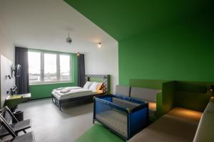 une chambre verte avec un lit et un canapé dans l'établissement MEININGER Hotel Dresden Zentrum, à Dresde