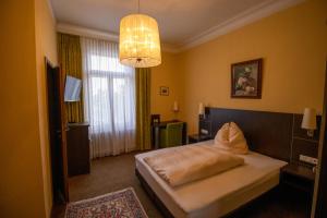 ein Hotelzimmer mit einem Bett und einem Kronleuchter in der Unterkunft Hotel Villa Glas in Erlangen