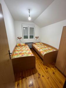 zwei Betten in einem Zimmer mit Holzboden in der Unterkunft Apartman Branko in Kolašin