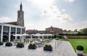 einen Innenhof mit Tischen und Sonnenschirmen vor einem Gebäude in der Unterkunft Stanbrook Abbey Hotel, Worcester in Worcester