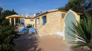 a house with a patio with blue chairs and an umbrella at Nature Beach Resort Quinta Al-Gharb in Vila do Bispo