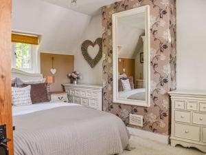 a bedroom with a bed and a large mirror at Greenbank Cottage in Burley