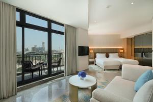 ドバイにあるArabian Park Dubai, an Edge by Rotana Hotelのベッドとリビングルームが備わるホテルルームです。