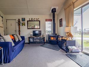 ein Wohnzimmer mit einer blauen Couch und einem Kamin in der Unterkunft Alpine Way Cottage - Ohakune Holiday Home in Ohakune