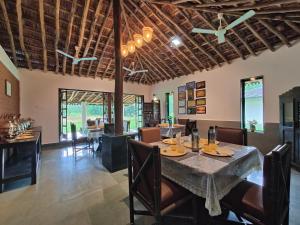 a dining room with a table and chairs at SaffronStays Mango Huts by the River, Pali in Jambhulpāda