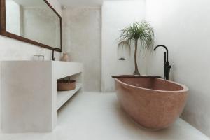 a bathroom with a large copper tub with a plant in it at Casa Sula Bali in Uluwatu +32 photos