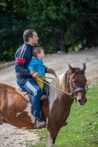 a man riding a horse with a child on it at Etno Village Vojnik in Šavnik