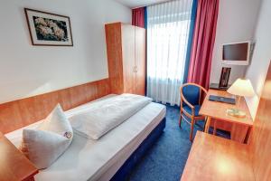 a hotel room with a bed and a desk at Hotel Antares in Munich