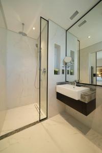 ein weißes Bad mit einem Waschbecken und einer Dusche in der Unterkunft Arabian Park Dubai, an Edge by Rotana Hotel in Dubai