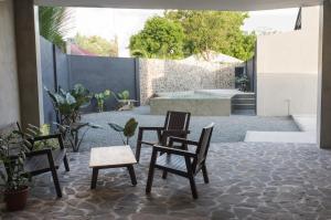 a patio with three chairs and a table and a tub at Pobla Hotel in Oslob