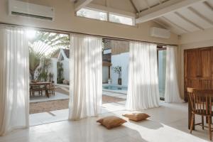 a living room with white curtains and a large window at Casa Sula Bali in Uluwatu