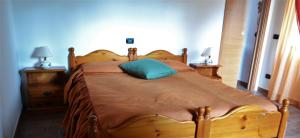 a large wooden bed with a blue pillow on it at Agriturismo Le oche selvatiche in Lauzacco