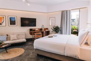 una camera d'albergo con un grande letto bianco e un divano di Dave by the Beach Loutraki, a member of Brown Hotels a Loutraki