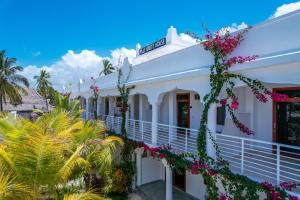 a white building with pink flowers on it at Paje White House Boutique Hotel in Paje