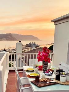 a table with food and flowers on a balcony at Bougainvillea House - The Heart of Simonstown in Simonʼs Town
