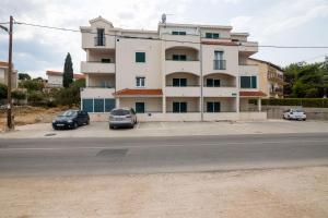 a building with two cars parked in a parking lot at Apartment Zorica in Trogir