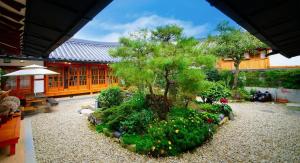 un jardín con un árbol y flores frente a un edificio en Jeonju Hanok Village Beautiful Garden House, en Jeonju