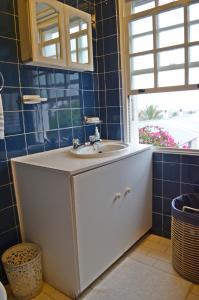 baño con lavabo blanco y azulejos azules en Bougainvillea House - The Heart of Simonstown en Simonʼs Town