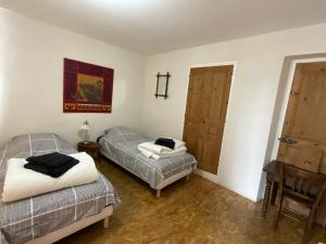 a room with two beds and a table and two doors at La Castanea, Charmante maison au pied du Granier in Chapareillan