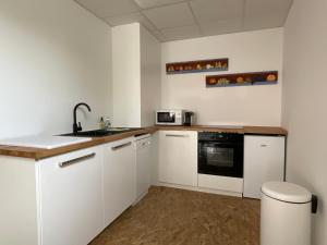 a kitchen with white cabinets and a sink at La Castanea, Charmante maison au pied du Granier in Chapareillan