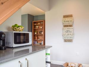 a kitchen with a microwave and a shelf with apples at Little Bank Cottage in Lane to Richards Castle