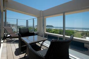 einen Balkon mit einem Tisch, Stühlen und Fenstern in der Unterkunft BREATH HOTEL in Kamakura