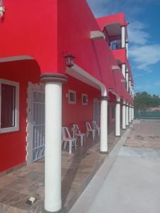 a red building with white columns and chairs on a patio at Hacienda Gallardos 104-3 in San Carlos