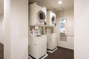 a laundry room with two washers and a dryer at Hotel Axiainn Osaka-Uehonmachi in Osaka