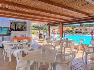 a restaurant with tables and chairs and a pool at Pleasant apartment in Aglientu with shared pool in Aglientu