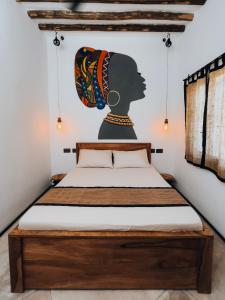 a bedroom with a bed with a painting of a woman at BaraBara Eat&Sleep - Eco Boutique Hotel in Paje