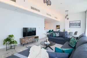 a living room with a blue couch and a tv at HiGuests - Spacious Apt Near Zabeel Park With Panoramic Views in Dubai