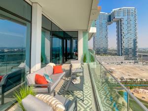 - un balcon avec un canapé et des chaises dans un bâtiment dans l'établissement HiGuests - Spacious Apt Near Zabeel Park With Panoramic Views, à Dubaï