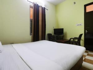 een slaapkamer met een wit bed en een kamer met stoelen bij Goroomgo Blue Moon Resort Lake View Mall Road Bhimtal - Best Seller in Nainital