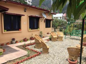 eine Terrasse mit Korbstühlen vor einem Haus in der Unterkunft Goroomgo Blue Moon Resort Lake View Mall Road Bhimtal - Best Seller in Nainital