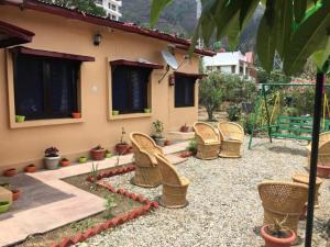 a patio with wicker chairs in front of a house at Goroomgo Blue Moon Resort Lake View Mall Road Bhimtal - Best Seller in Nainital