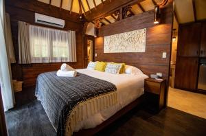 ein Schlafzimmer mit einem Bett in einem Zimmer mit Holzwänden in der Unterkunft Selva Armonia Immersive Jungle Resort in Uvita