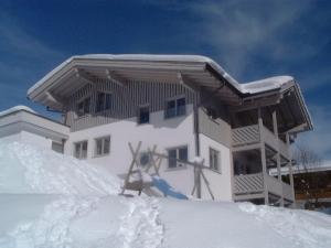 a building with snow on the ground in front of it at Chalet Birkenhof in Saalbach Hinterglemm