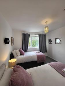 a bedroom with two beds and a window at Emerald House in Luton