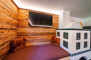 a room with a flat screen tv on a wooden wall at Sonnentalhof in Itter