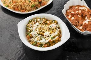 uma tigela de comida numa mesa com outros pratos de comida em The Hosteller Agra em Agra